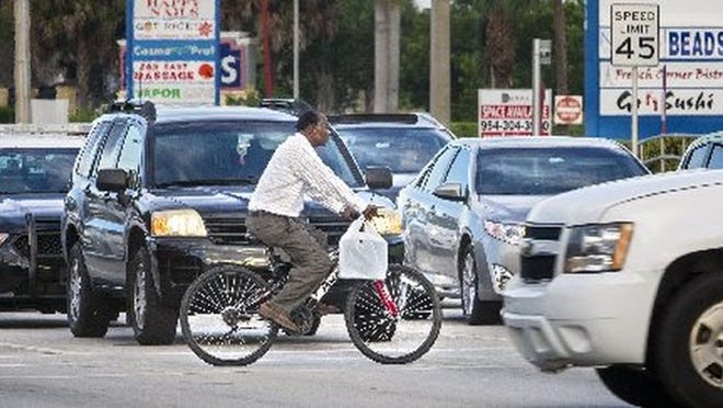 A bicyclist crosses Okeechobee Boulevard. (Lannis Waters / The Palm Beach Post)