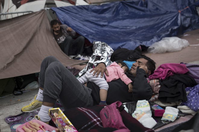 A migrant father and child, who traveled with the annual caravan of Central American migrants, rest where they set up camp to wait for access to request asylum in the US, outside the El Chaparral port of entry building at the US-Mexico border in Tijuana, Mexico, Monday, April 30, 2018. About 200 people in a caravan of Central American asylum seekers waited on the Mexican border with San Diego for a second straight day on Monday to turn themselves in to U.S. border inspectors, who said the nation's busiest crossing facility did not have enough space to accommodate them. (AP Photo/Hans-Maximo Musielik)
