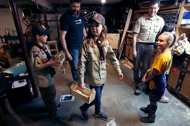 FILE - In this March 1, 2018, file photo, Tatum Weir, center, carries a tool box she built as her twin brother Ian, left, follows after a Cub Scout meeting in Madbury, N.H. Fifteen communities in New Hampshire are part of an "early adopter" program to allow girls to become Cub Scouts and eventually Boy Scouts. For 108 years, the Boy Scouts of America's flagship program for older boys has been known simply as the Boy Scouts. With girls soon entering the ranks, the BSA says that iconic name will change to þÄúScouts BSA.þÄù The change will take effect in February 2019. (AP Photo/Charles Krupa, File)