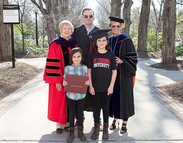 Marcia G. Welsh, right, president of East Stroudsburg University and Joanne Z. Bruno, left, provost and vice president for academic affairs congratulate Mehmet Barzev, center, and his daughters on his upcoming graduating from ESU. [EAST STROUDSBURG UNIVERSITY PHOTO]