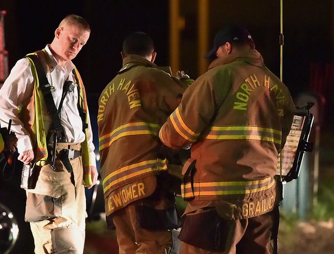 Emergency personnel respond to Quinnipiac Avenue in North Haven, Conn., at the scene of explosion and reported stand-off Wednesday evening, May 2, 2018. A barn behind a house in Connecticut exploded Wednesday night while police and a SWAT team were negotiating with a man who had taken his wife and family hostage, leaving several officers injured, officials said. (Catherine Avalone/New Haven Register via AP)