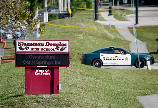 Law enforcement officers block off the entrance to Marjory Stoneman Douglas High School, in Parkland, Fla., the day after a deadly shooting at the school. [WILFREDO LEE/AP FILE]
