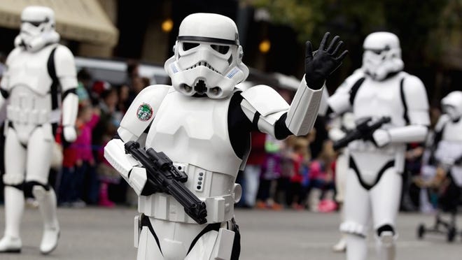 A stormtrooper with The 501st Legion waves to the crowd during the 25th Annual Chuy's Children Giving to Children Parade on Congress Avenue on Saturday, November 30, 2013. Gifts collected at the event go toward Operation Blue Santa. DEBORAH CANNON / AMERICAN-STATESMAN