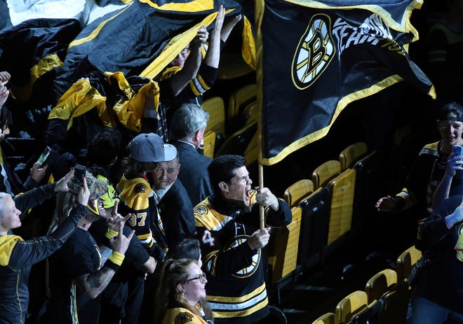 New England Patriots great Tedy Bruschi waves a Bruins banner before Friday night's game.