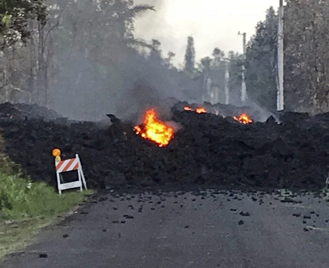 This photo provided by Hawaii Electric Light shows lava flowing over Mohala Street in the Leilani Estates area near Pahoa on the Big Island of Hawaii Friday, May 4, 2018. Nearly 1,500 people have fled from their homes after Hawaii's Kilauea volcano sent molten lava chewing through forests and bubbling up on paved streets in an eruption that one resident described as "a curtain of fire." (Hawaii Electric Light via AP)