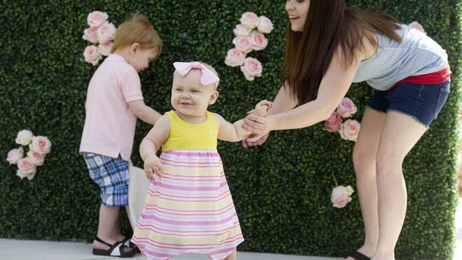 Amber Johnson, right, tries to pose her children Dayton, 3, and Nora, 1, for a photo during the Royal Poinciana Plaza Easter Egg Hunt March 31. (Meghan McCarthy / Daily News)