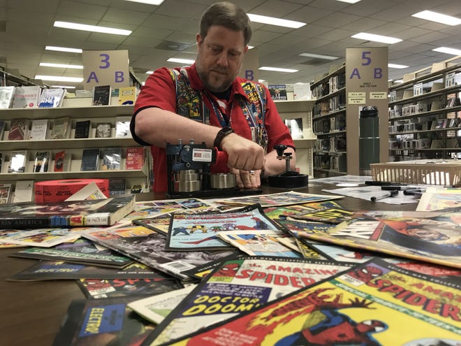 Ensley Guffey transforms worn out comics into super hero pins at the Comic Book Day at Cleveland Memorial Library Saturday. [Joyce Orlando/The Star]