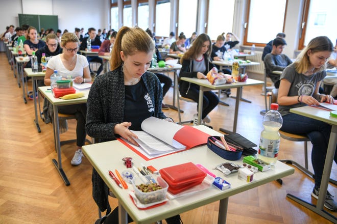 FILE - In this April 18, 2018 file photo students take a look at an exam test at the Graf-Zeppelin-Gymnasium in Friedrichshafen, Germany. High school students in Germany have been complaining in an online petition about their final exam in English saying the test was much harder than in previous years. As of Sunday May 6, 2018, students in the southwestern state of Baden-Wuerttemberg had gathered almost 36,000 signatures even though only 33,500 participated in last month’s statewide exam. The final high school exams in Germany - called Abitur - are a rite of passage that all students who want to enter university have to pass. (Felix Kaestle/dpa via AP,file)