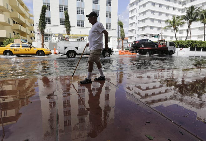 Louis Fernandez walks along Collins Avenue from his apartment to a nearby restaurant during high tide flooding in September 2015 in Miami Beach. Such flooding is expected to become increasingly prevalent in coastal communities in the coming decades.

[AP archive / Lynne Sladky]