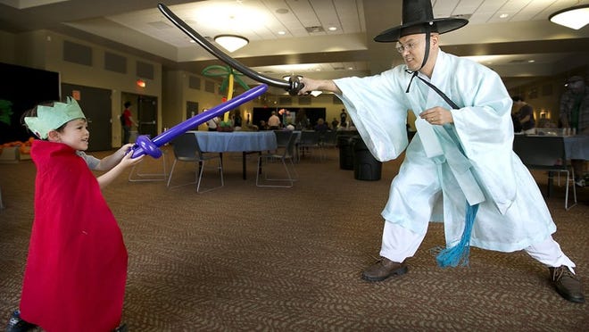 Balloon maker Teddy Kim has a sword duel with Khoi Hoang, 2, after he outfitted the youngster with his choice of weapon during CelebrASIA Austin. RALPH BARRERA/ AMERICAN-STATESMAN 2015