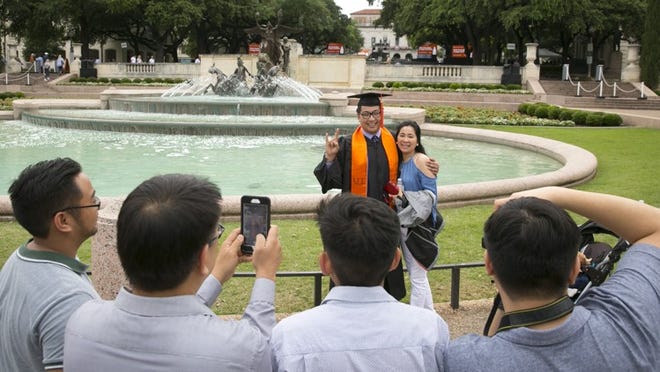 Ronald Maninang, who graduated with a Bachelor of Science degree in Aerospace Engineering, takes a photo with his mother, Jennifer Maninang, at the Littlefield Fountain before the university-wide graduation ceremony at UT on Saturday May 20, 2017. JAY JANNER / AMERICAN-STATESMAN
