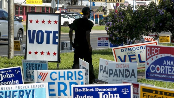 A man walks past political campaign signs at a polling location at the Travis County offices on Airport Boulevard on March 6. JAY JANNER / AMERICAN-STATESMAN