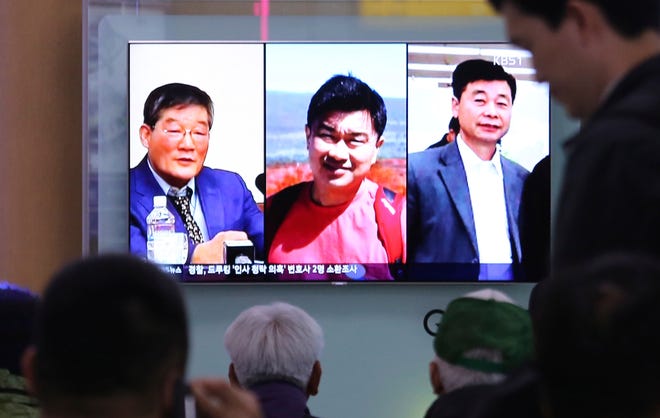 In this May 3, 2018 photo, people watch a TV news report on screen, showing portraits of three Americans, Kim Dong Chul, left, Tony Kim and Kim Hak Song, right, detained in the North Korea, at the Seoul Railway Station in Seoul, South Korea. President Donald Trump says Secretary of State Mike Pompeo is on his way back from North Korea with three American detainees, saying they "seem to be in good health." (AP Photo/Ahn Young-joon)