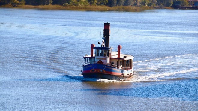 A ferry cruises on the Savannah River passing by River Street restaurants and antiques stores. Photo by Cheryl Blackerby