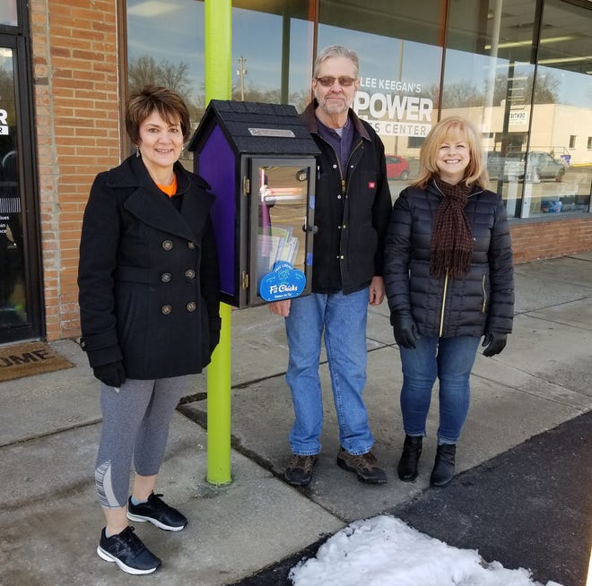 Claudia Amrhein, Wayne Luke and Donna Friend stand next to the Little Free Library recently installed in Ravenna.