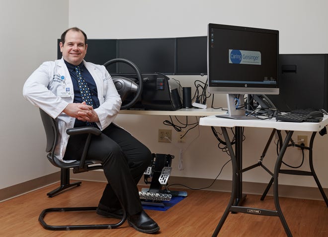 Dr. Wayne Finney, neurologist, is seated in front of a simulated driving program and discusses its benefit to Geisinger patients in the neurology Memory Care program. Finney practices in Scranton and Mount Pocono. [GEISINGER PHOTO]