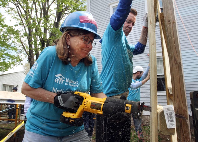 Women Build volunteer Janice Tetreault of North Kingstown cuts a section off a wooden fence as Bob Walsh of Tiverton holds the fence steady. [The Providence Journal / Bob Breidenbach]