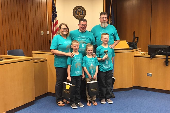 Sheryl, left, and Matt Mohr, right, pose in the courtroom with Probate Judge Gregg Iddings, center, and the Mohrs' three newest additions, Olivia Grace, 8; Landon, 9; and Dawson, 12.