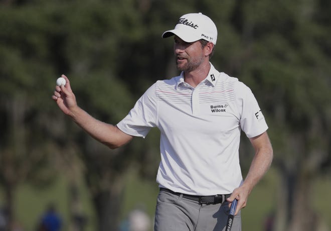Webb Simpson holds up his ball on the 18th green during The Players Championship after carding a 63, which tied the course record. [AP PHOTO/LYNNE SLADKY]