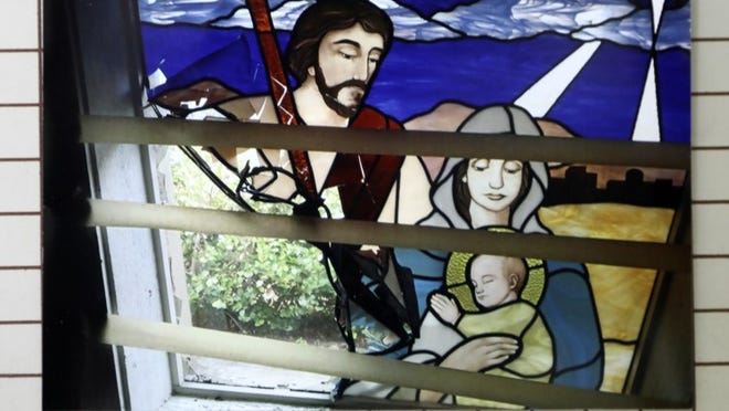 Photo of a photo of a stained glass window that was smashed at Church of Our Savior in Boynton Beach. (Bruce R. Bennett / The Palm Beach Post)