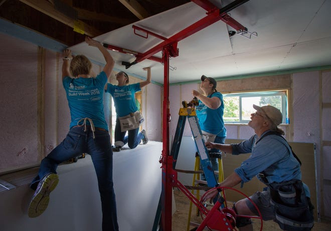 Northwest Community Credit Union employees Sheree Milligan (left), Carmen Harrell (center) and Katrina Banton work hanging drywall under the supervision of Peter Kugler inside a Habitat for Humanity house under construction in Eugene. [Brian Davies/The Register-Guard] - registerguard.com