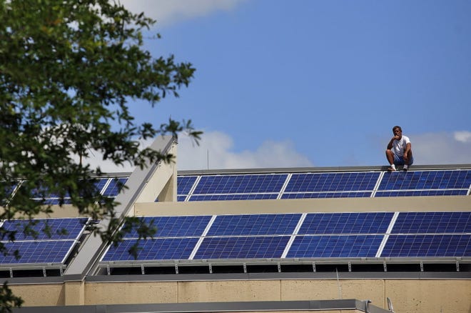 A worker takes a break from wiring solar panels on the roof of the Gainesville Regional Airport. [Gainesville Sun/File]