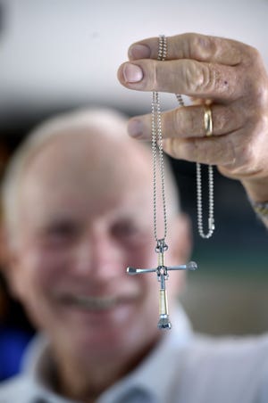 Shalimar resident Ron Gross holds one of the crosses he makes out of horseshoe nails and wire. Gross places the crosses on bead necklaces, which he then gives away. [DEVON RAVINE/DAILY NEWS]