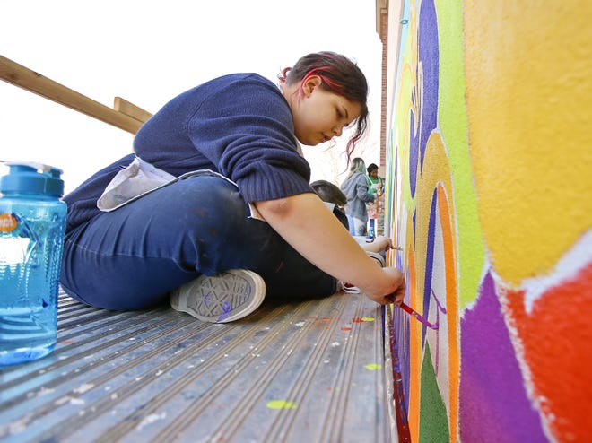 Max Fuentes helps paint a mural on the front of Natural Grocers on 23rd Street in Lawrence. [Chris Neal/The Capital-Journal]