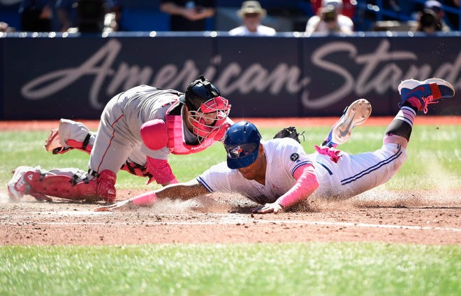 Toronto Blue Jays' Yangervis Solarte, foreground, is tagged out by Boston Red Sox catcher Christian Vazquez at home plate during seventh-inning baseball game action in Toronto, Sunday, May 13, 2018. (Nathan Denette/The Canadian Press via AP)