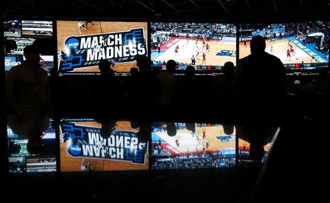 In this March 15, 2018 photo, people watch coverage of the first round of the NCAA college basketball tournament at the Westgate Superbook sports book in Las Vegas. The Supreme Court has struck down a federal law that bars gambling on football, basketball, baseball and other sports in most states, giving states the go-ahead to legalize betting on sports.