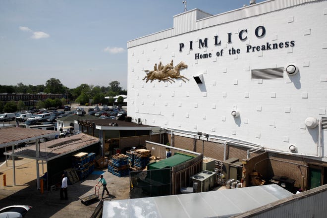 People walk outside of a building at Pimlico Race Course as preparations take place for the Preakness Stakes horse race, Tuesday, May 15, 2018, in Baltimore. Pimlico Race Course is getting all gussied up again this week, ready to host the Preakness on a day that will enable the 148-year-old track to survive another year. (AP Photo/Patrick Semansky)