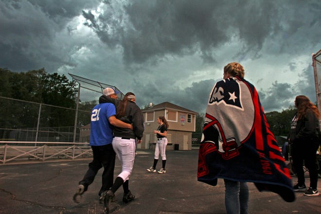 Players coaches and fans head for cover as lightning disrupts the Pilgrim vs. Cranston West softball game at Brayton Field in Cranston on Tuesday. A downpour soon followed causing the cancellation of the game. [The Providence Journal / David DelPoio]