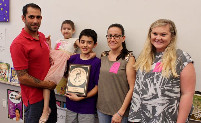 Rymfire Elementary student Diego Costa, center, and his family stand with Megan Then, right, of The Leukemia and Lymphoma Society. Diego received a plaque recently recognizing his efforts in raising money for the cause. [Photo Provided]