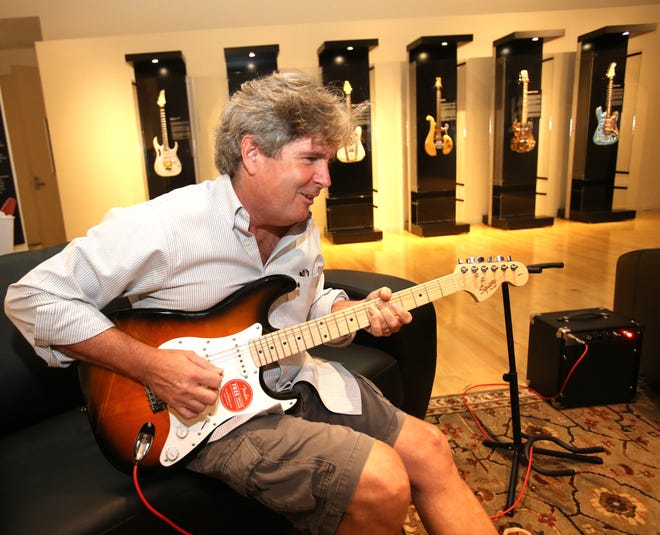 HP Newquist, executive director of the National GUITAR Museum in New York City, plays a Fender Squier Stratocaster electric guitar Wednesday that is part of the "Medieval To Metal: The Art & Evolution Of The GUITAR" exhibit, shown behind him at the Appleton Museum of Art in Ocala. The exhibit of guitars ranging from the Lute, the immediate predecessor to the guitar, the intricately inlaid Moorish oud and  six-foot long Renaissance theorbo, to the modern-day electric guitars such as the Ibanez Jem or the B.C. Rich "Warlock," will be open to the public from Saturday to Sept. 2. [Bruce Ackerman/Staff photographer]