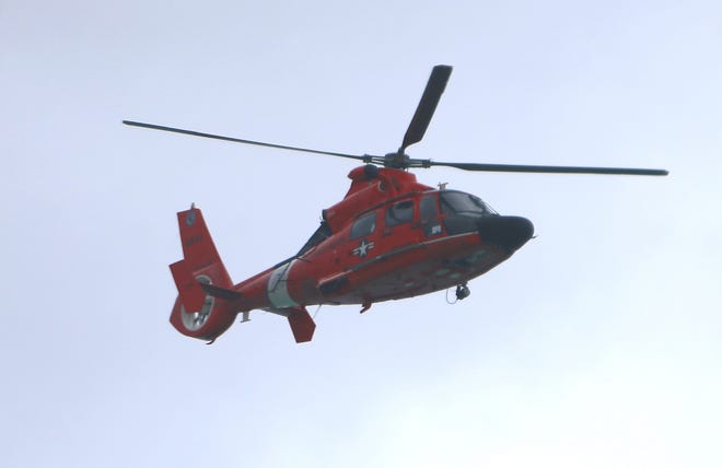 A Coast Guard helicopter flies overhead as crews search for a lost swimmer on Tuesday at the beach near the City Pier.  [PATTI BLAKE/THE NEWS HERALD]