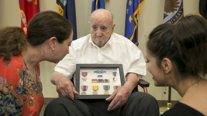 World War II Army veteran Julio Izquierdo, 100, shows his medals to his granddaughters Naomi Izquierdo-Martinez, left, and Stephyne Williams at a ceremony at the VA Austin Outpatient Clinic on Friday. Izquierdo accepted eight medals that he never received after the war, including the Bronze Star with Oak Leaf Cluster, Purple Heart, Army Good Conduct Medal, Presidential Unit Citation, American Defense Service Medal, European-African-Middle Eastern Campaign Medal, World War II Victory Medal and the Combat Infantryman Badge. He was surrounded by eight of his nine children, and several grandchildren. JAY JANNER / AMERICAN-STATESMAN