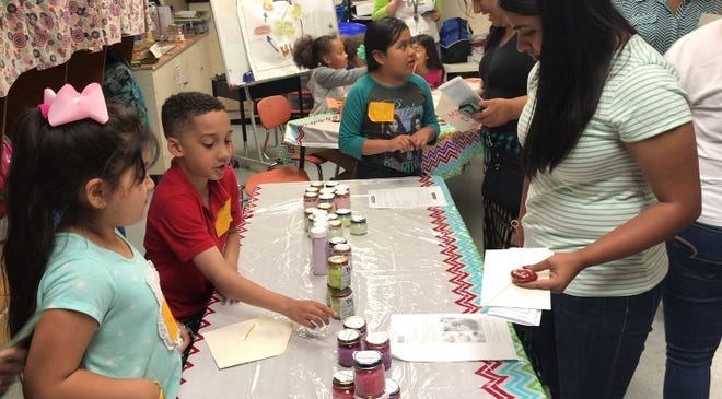 Estephania Leon, 8, far left, Kamari O'Danial, 8, left, and Gabriella Arcos, 7, center, talk to parents about the ingredients in their homemade bath salts and scrubs during Eastlawn Elementary School's annual Market Day. [JESSICA WILLIAMS / TIMES-NEWS]