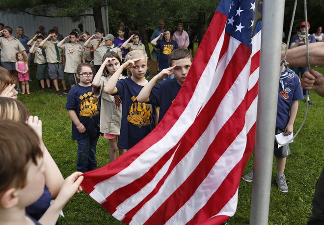 Girls and boys salute during the flag-lowering ceremony at the Boy Scouts of America Pack 74 spring campout in Galena on Saturday. The Clintonville-based pack was one of the first in the country to allow girls to join in a pilot program. Girls can officially join Cub Scouts nationwide starting June 1. [Adam Cairns/Dispatch]