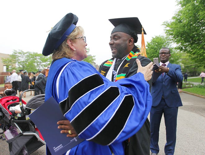 Katherine Paquette, left, of Fall RIver, an assistant clinical professor in the college of nursing, congratulates Isaiah Mansan, of Providence, who earned a degree in nursing. [The Providence Journal / Glenn Osmundson]