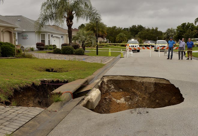 A sinkhole is shown after opening in the road at the intersection of McAlpin Street and McLawren Terrace in The Villages, Florida on Monday, May 21. Four sinkholes have opened up in a fast-growing retirement community in Florida, including one in front of a home that was abandoned months ago because of an earlier sinkhole. A spokeswoman for the Marion County Sheriff's Office says the new sinkholes opened up Monday in The Villages following a week of nonstop rain in central Florida. [ GEORGE HORSFORD / AP ]