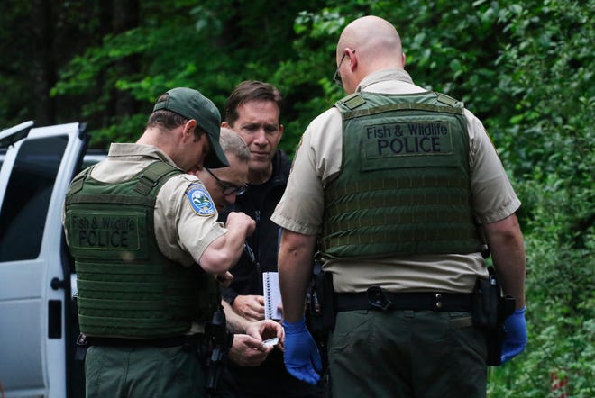 Washington State Fish and Wildlife Police confer with an individual from the King County Medical Examiner's Office and a King County sheriff's deputy on a remote gravel road above Snoqualmie after the fatal cougar attack Saturday. [Alan Berner /The Seattle Times via AP]