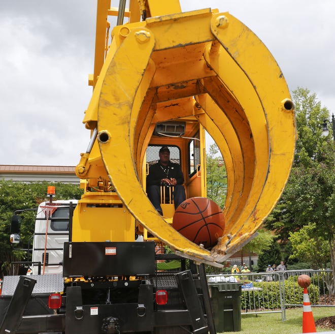 Edward Binion uses a knuckle boom to play a game of basketball during the "Road-EO," an observance of National Public Works Week at Government Plaza on Tuesday, celebrating publics works employees across the country. The operator plucks the ball from atop a traffic cone and then dunks it into a waiting garbage can to score. [Staff Photo/Gary Cosby Jr.]