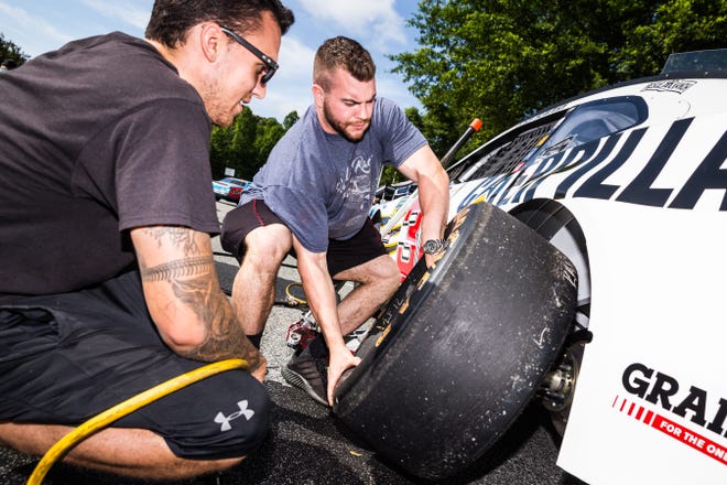 Austin Taylor (left) holds the impact wrench as Corbin Martin adds a tire to Ryan Newman's Caterpillar Chevrolet during Richard Childress Racing Fan Appreciation Day on Wednesday morning at RCR Museum & Team Store. [Dan Busey/The Dispatch]