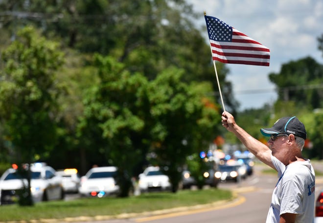 Mark Bronstein pays his respects as the funeral procession of Jacksonville police officer Lance Whitaker makes its way down Hendricks Avenue to Oaklawn Cemetery Wednesday, May 23, 2018 in Jacksonville, Florida. Whitaker was killed May 15 in a one vehicle crash while on duty and responding to a call. [Will Dickey/Florida Times-Union]