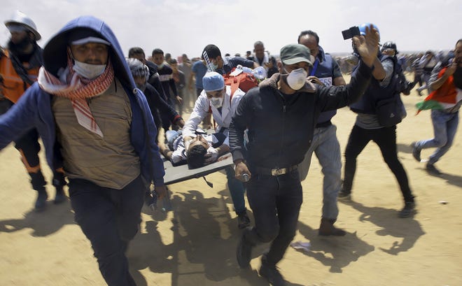 Palestinian medics and protesters evacuate a wounded youth during a May 14 protest at the Gaza Strip's border with Israel. [AP Photo/Adel Hana]
