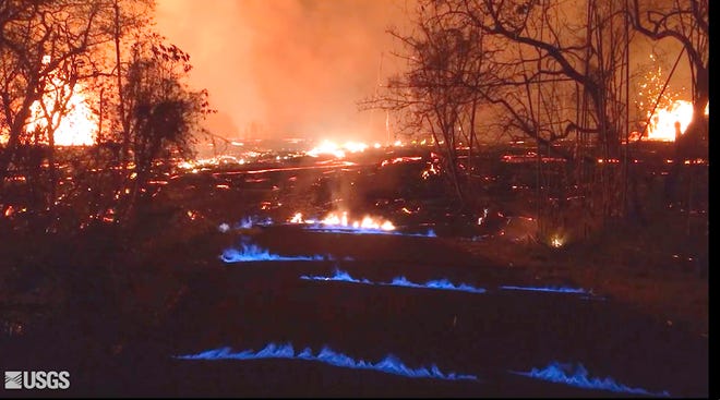 This photo from video from the U.S. Geological Survey shows blue burning flames of methane gas erupting through cracks on Kahukai Street in the Leilani Estates neighborhood of Pahoa on the island of Hawaii during the overnight hours of Wednesday, May 23, 2018. When lava buries plants and shrubs, methane gas is produced as a byproduct of burning vegetation. Methane gas can seep into subsurface voids and explode when heated, emerging from cracks in the ground several feet away from the lava. (U.S. Geological Survey via AP)