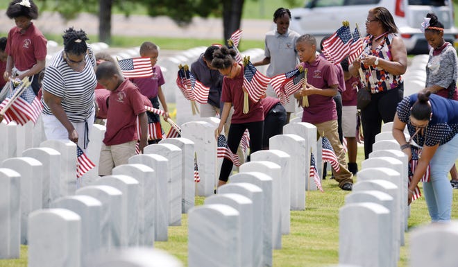 Students and teachers from the afterschool program at America's Little Leaders Junior Academy came out Thursday afternoon to volunteer their time placing flags at the Jacksonville National Cemetery. [Bob Self/Florida Times-Union]