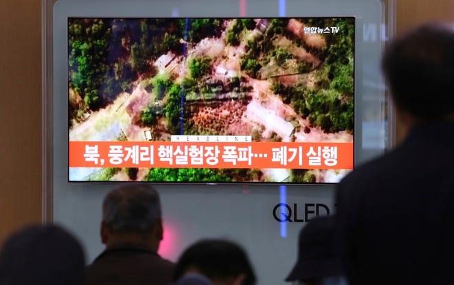 People watch a TV screen showing a satellite image of the Punggye-ri nuclear test site in North Korea during a news program at the Seoul Railway Station in Seoul, South Korea, Thursday, May 24, 2018. North Korea carried out what it said is the demolition of its nuclear test site Thursday, setting off a series of explosions over several hours in the presence of foreign journalists.The signs read: " North Korea demolishes nuclear test site." (AP Photo/Ahn Young-joon)