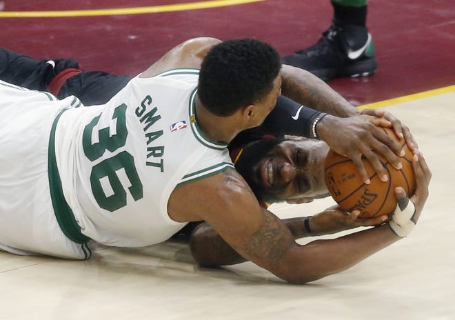 Cleveland's LeBron James, back, and Boston's Marcus Smart battle for the ball during the second half of Game 6 Friday. The Cavaliers won 109-99 to force a Game 7 back in Boston. [Ron Schwane/AP]