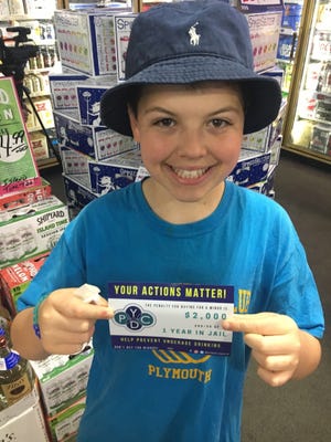 PLYMOUTH Boys & Girls Club member Bobby Barry delivers one of this year's Sticker Shock campaign stickers to Pioppi's Liquor store Thursday. Wicked Local photo/Rich Harbert